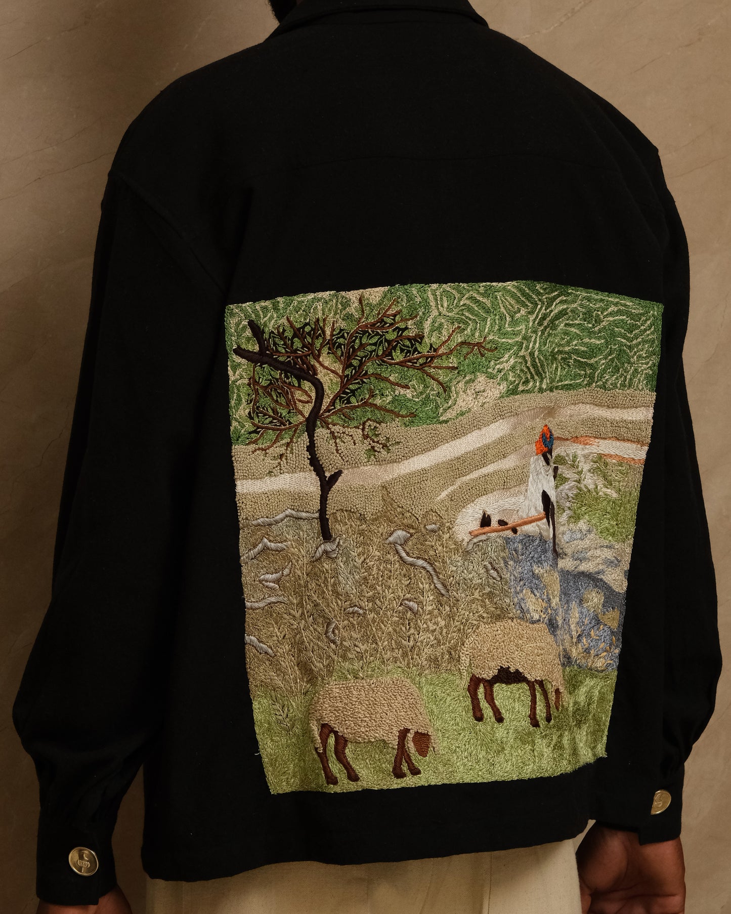 Sambhar 1.0 hand embroidered art shirt exploring pastoral landscapes through threadwork, shepherd imagery, grazing sheep motifs, and slow crafted textile storytelling shaped into a one of one wearable artwork