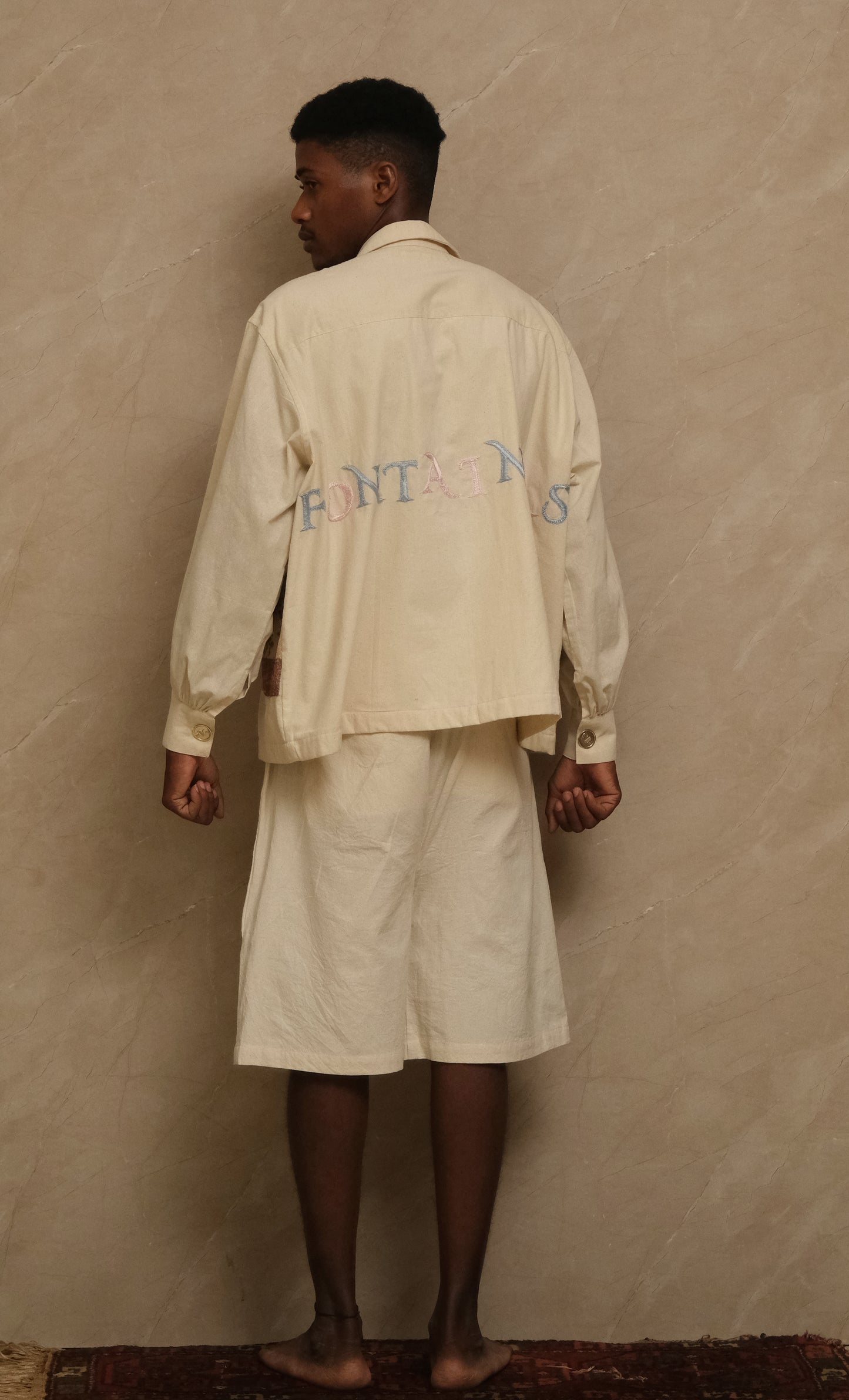 back of fontainhas hand-embroidered shirt, wearable art in unbleached cotton. Documentary style hand embroidery.  Silver Buttons. Latin Quarters. Archival Clothing. Image to Textile. Mix Media. 