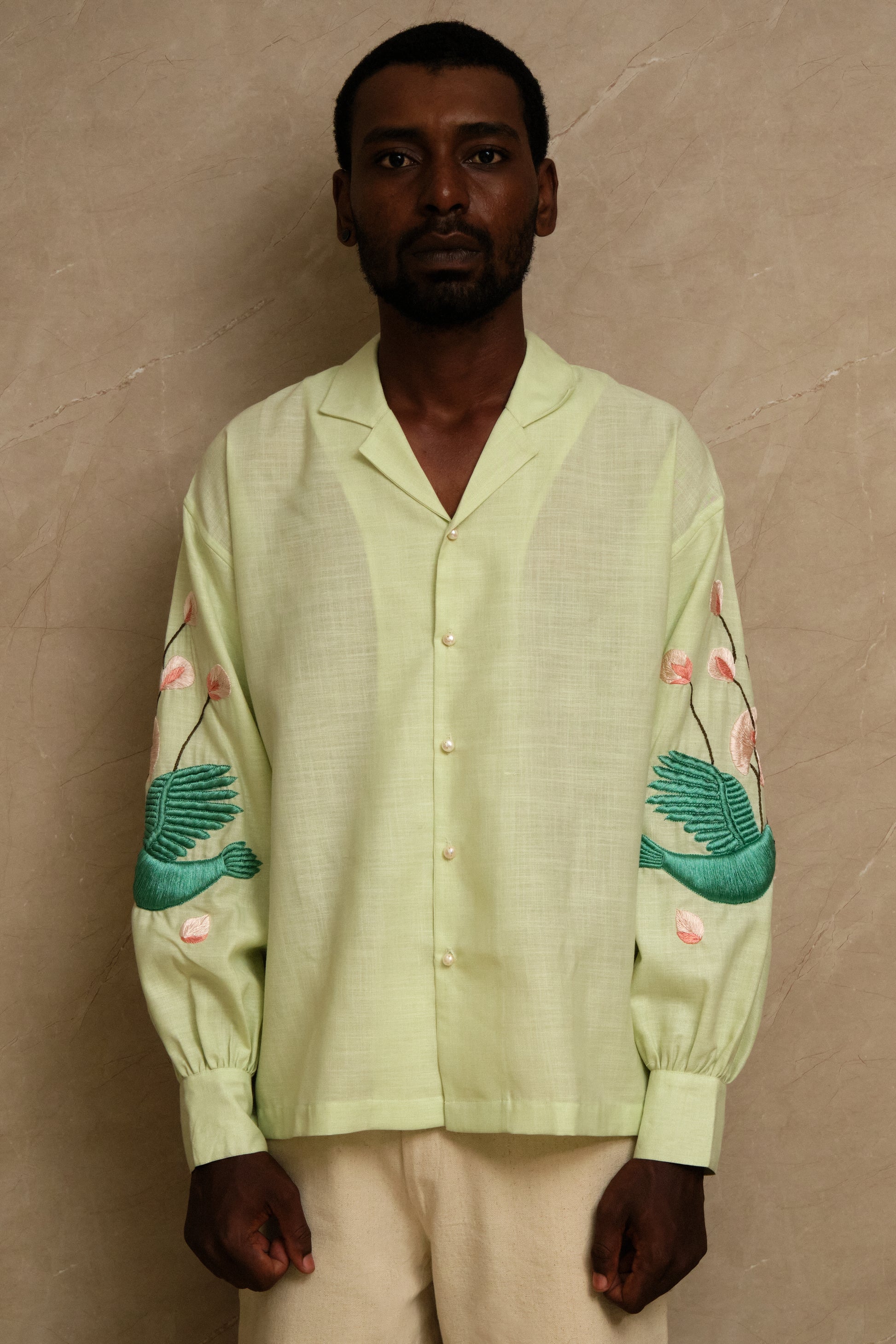 Hand embroidered Hiral Parind collector shirt showcasing detailed bird motifs, sage green silk fabric, handcrafted stitching, and heritage inspired wearable textile craftsmanship