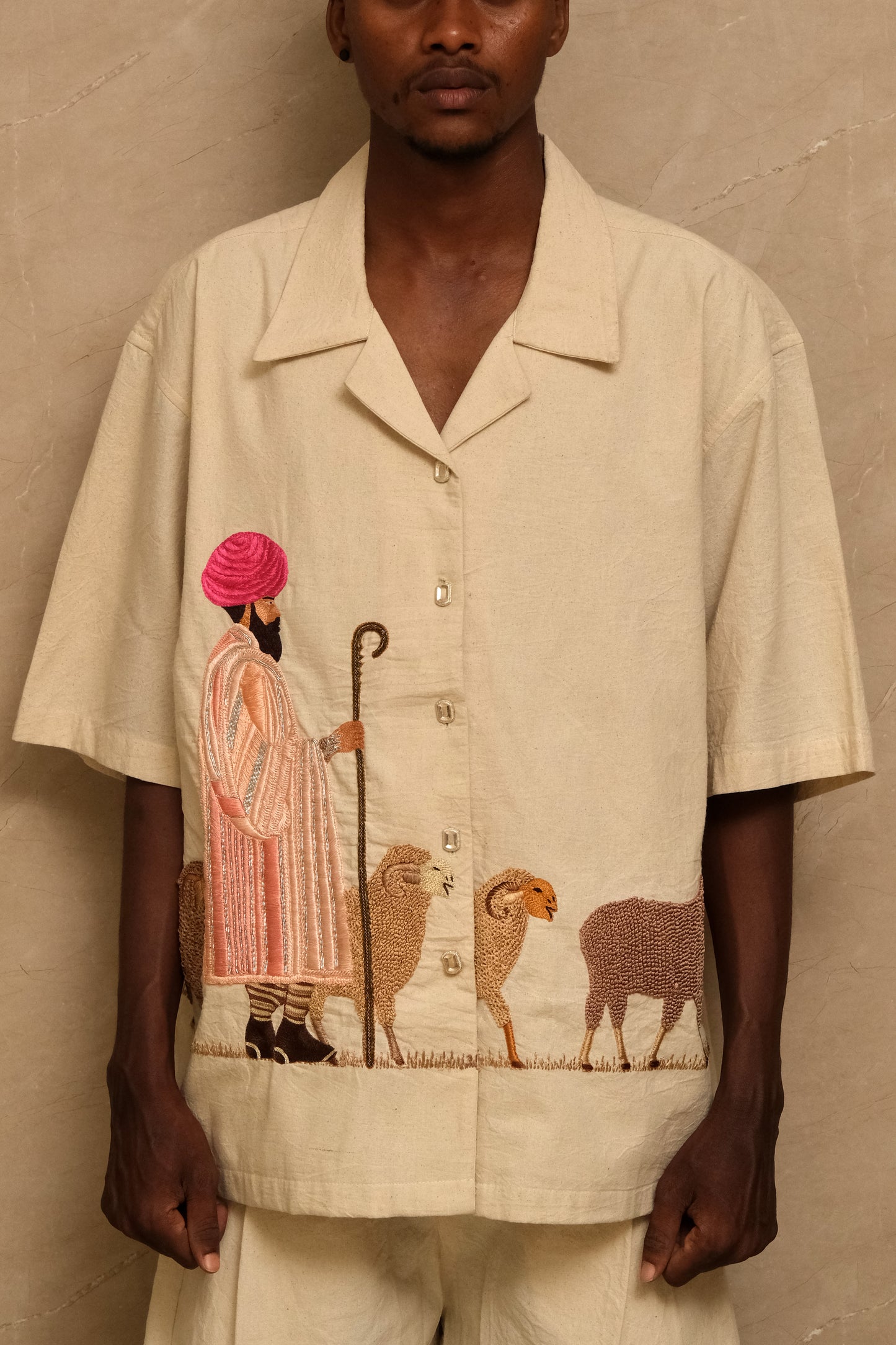 Sambhar 2.0 one of one hand embroidered art shirt featuring pastoral storytelling, shepherd and sheep motifs, metallic thread detailing, and slow crafted textile artwork photographed in an editorial setting